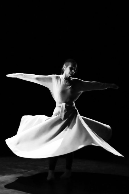 Un clown en costume avec moustache, regardant une plume blanche en vol.