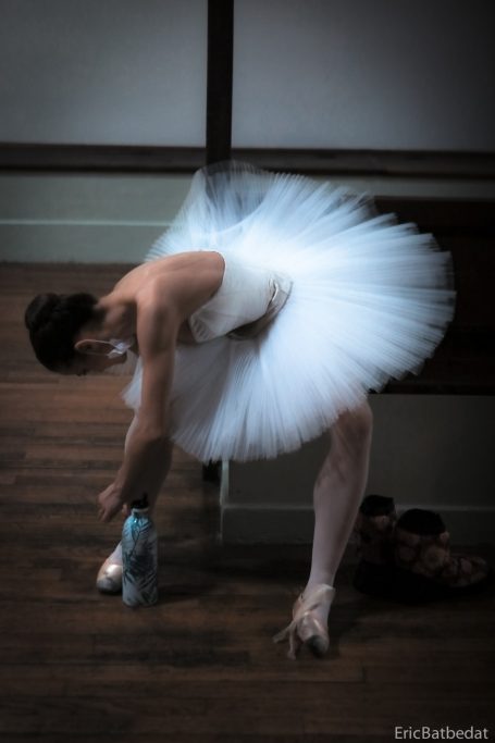 Une ballerine en tutu ajuste ses pointes dans un studio de danse.