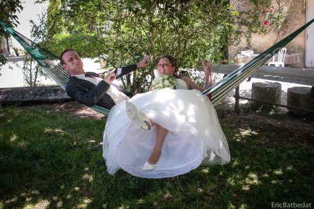 Un couple en costume et robe de mariée se relaxe sur des hamacs sous un arbre.