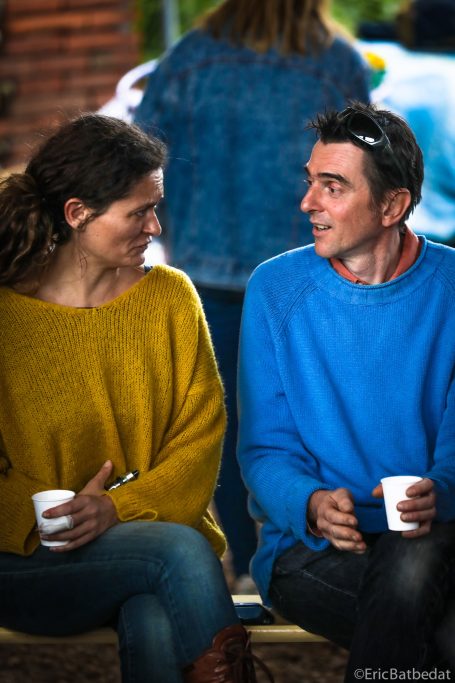 Deux personnes souriant et discutant, tenant des gobelets en papier.