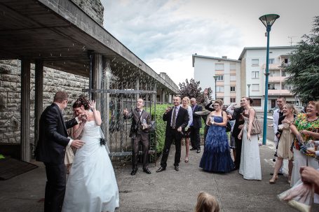 Couple se mariant, entouré d'invités dans une ambiance festive en extérieur.