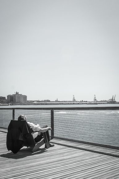 Homme détendu sur un ponton, regardant l'horizon au-dessus de l'eau.