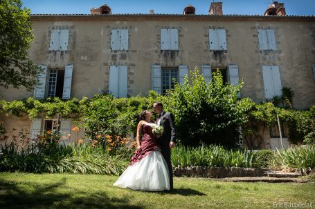 Mariage en extérieur, couple amoureux devant une maison ancienne, verdure environnante.