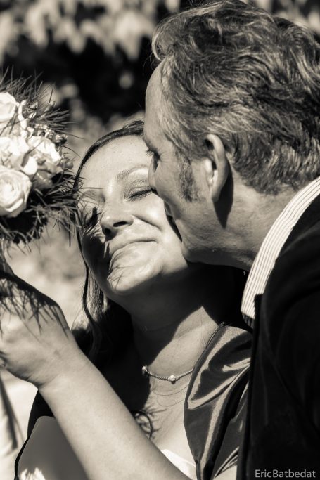 Un couple souriant partage un moment tendre lors d'un mariage en extérieur.