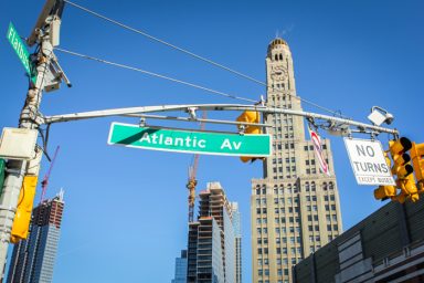 Panneau de signalisation "Atlantic Ave" avec un bâtiment en arrière-plan.