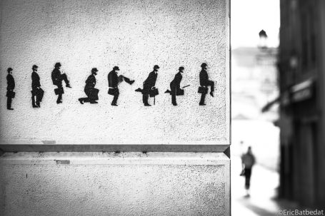Silhouettes de personnes marchant sur un mur, avec un individu en mouvement au loin.