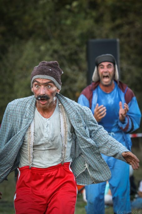 Une mariée en robe rouge et blanche avec un bouquet, posant avec un marié souriant.