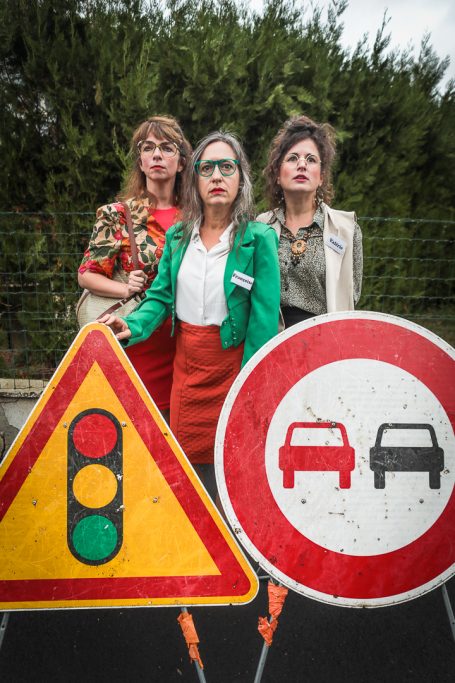 Trois femmes posant devant des panneaux de signalisation routière.