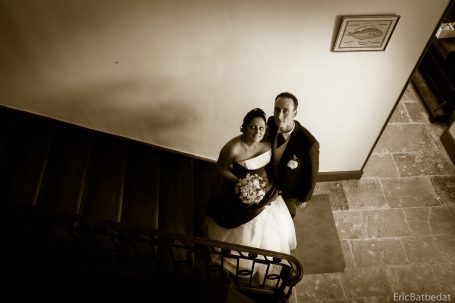 Couple en tenue de mariage, posant sur un escalier, en noir et blanc.