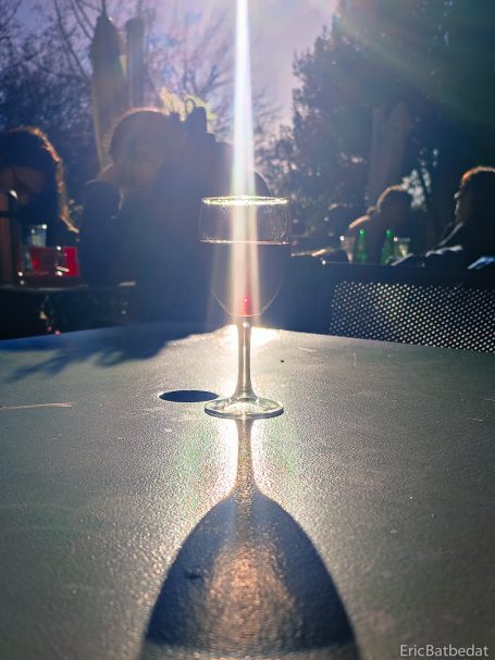 Un verre à pied sur une table, projetant une ombre allongée et éclairé par la lumière.