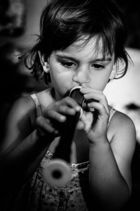 Une petite fille joue d'un instrument à vent, concentrée sur sa musique.