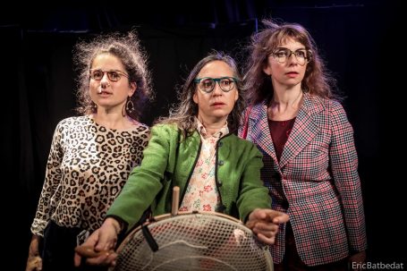 Trois femmes avec des lunettes, habillées de façon colorée, posant ensemble.