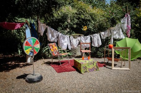 Un coin de jardin coloré avec des chaises, un arbre à jeu et des vêtements suspendus.